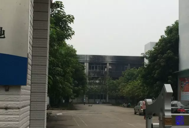 起火厂房外墙已被熏黑，工作人员戴着口罩。 市民王先生摄  